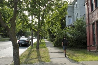 Person walking past East Hill apartments on East Seneca Street